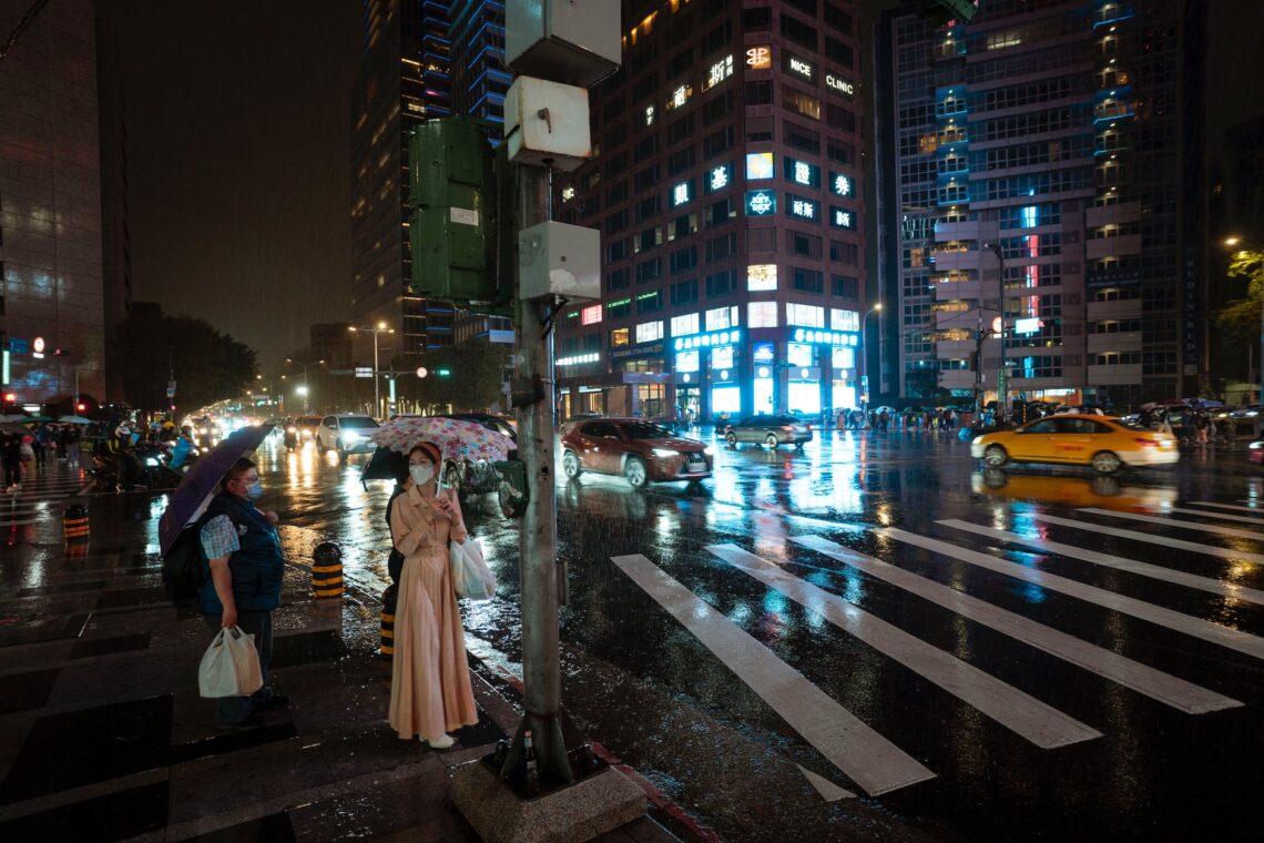 people standing on the street on a rainy night