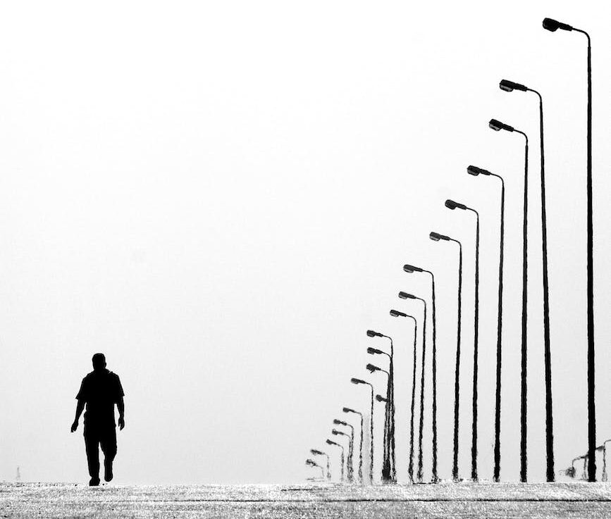 man walking near aligned lamp post